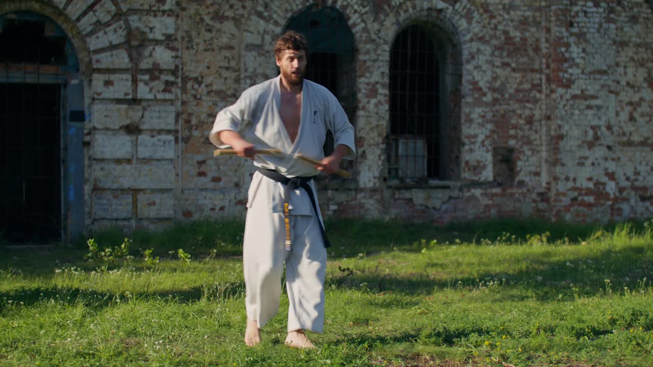 Uomo che pratica karate con i nunchaku all'aperto