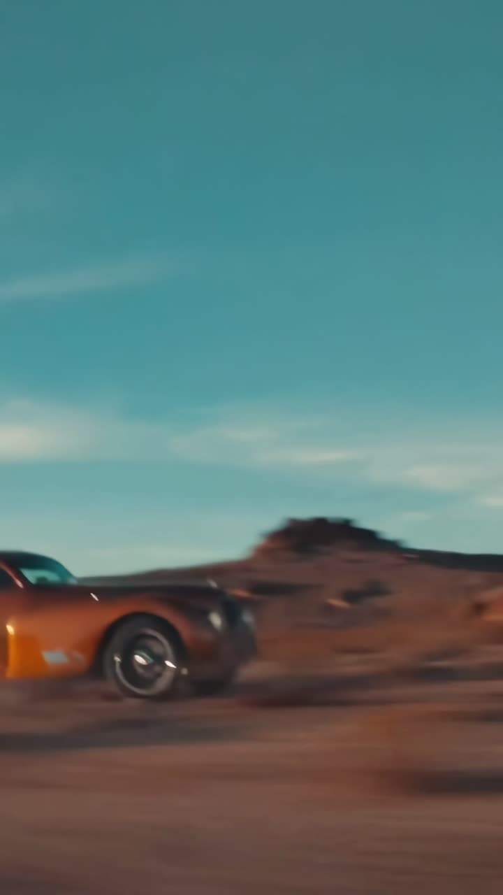 Dynamisk lavvinkelvideo af veteranbiler, der ræser på en støvet vej under en klar himmel