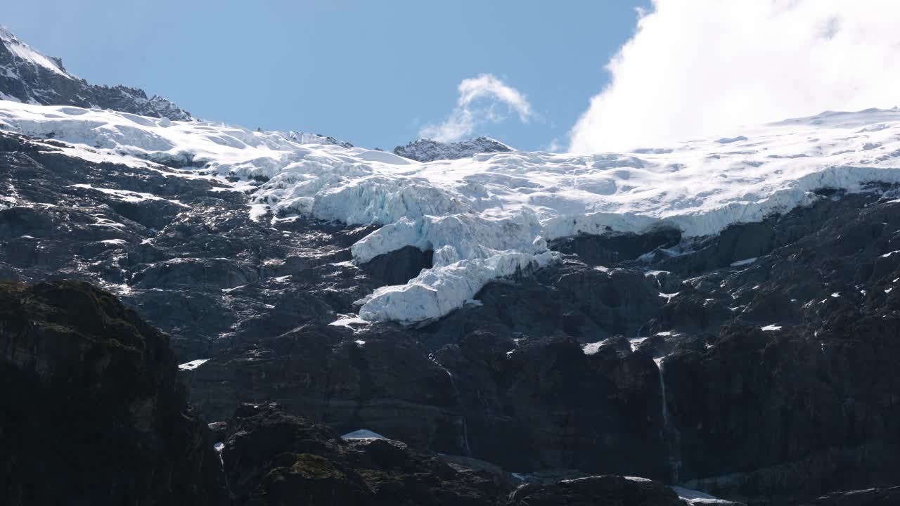 Wide view of snow covered mountains and glacier on a sunny day at Rob Roy Glacier, Wanaka, New Zealand.