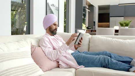 relaxing on sofa, man using tablet for browsing internet at home