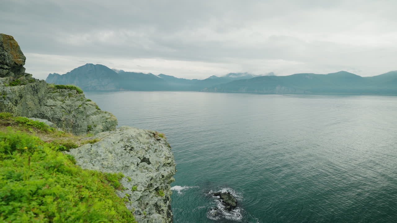 Kystudsigt over klippeklipper og tågede bjerge