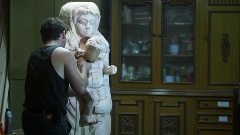 skilled artisan carefully carves the madonna and child statue from wood, shaping sacred details with precision in his workshop, preserving tradition and devotion through craftsmanship