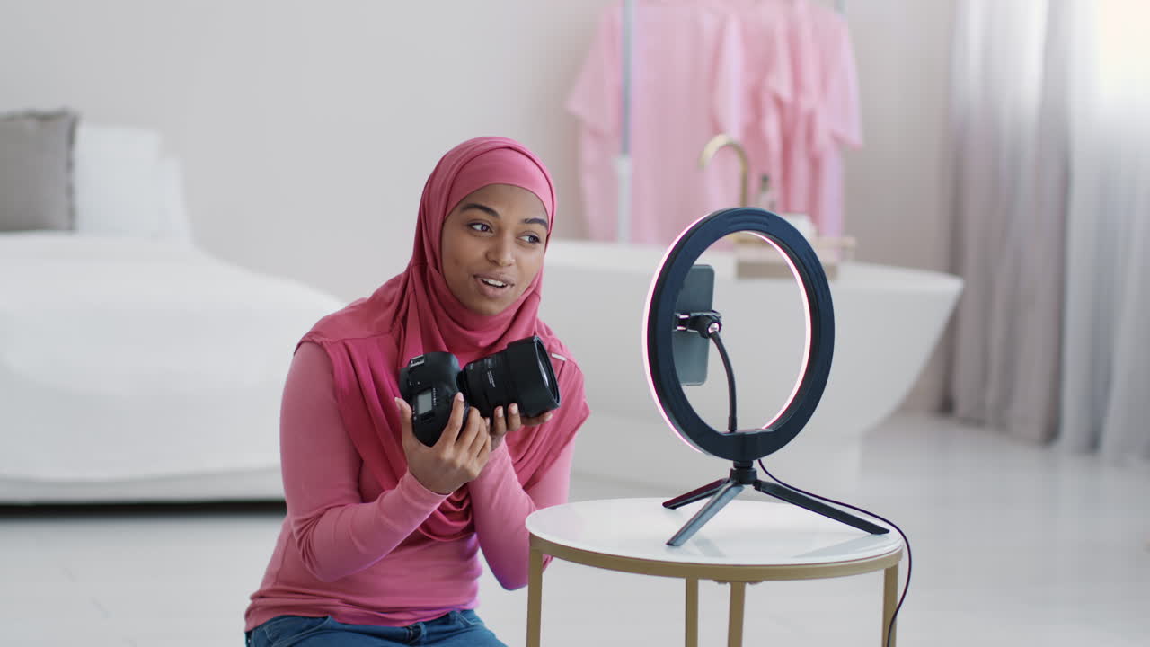 Donna con hijab che usa una fotocamera e un ring light per un tutorial video
