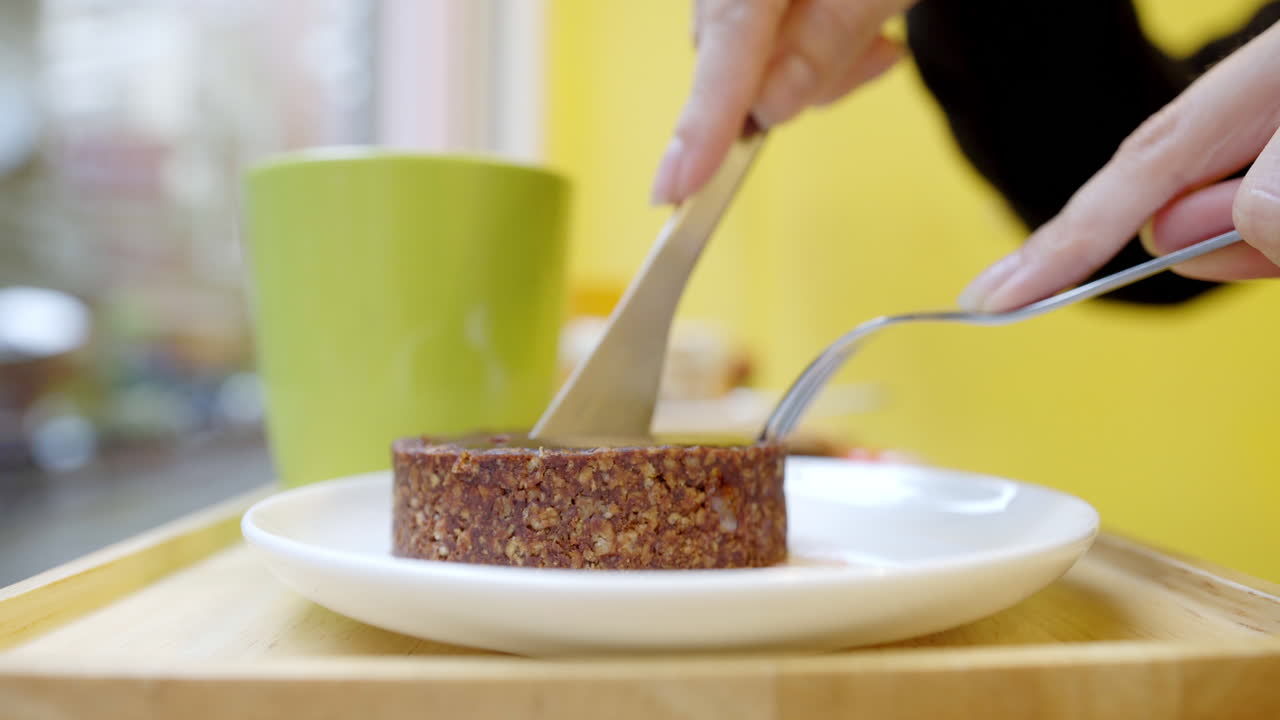 스테인리스 나이프와 포크로 단단한 비건 케이크를 자르는 여성 - 클로즈업 샷