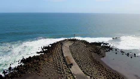 ocean waves crashing on tetrapod breakwater, pier on java coast aerial view
