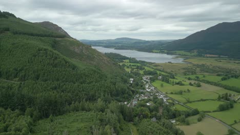 voando de montanhas arborizadas para terras agrícolas planas com o lago bassenthwaite à distância