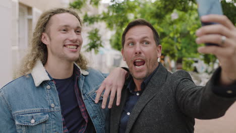 portrait of two men best friends posing making faces taking selfie photo using smartphone enjoying having fun in urban city background