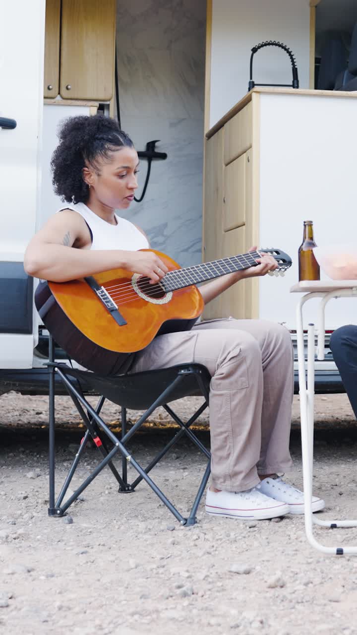 Woman playing guitar outdoors near camper van