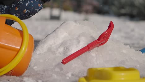 child playing in the snow with toys