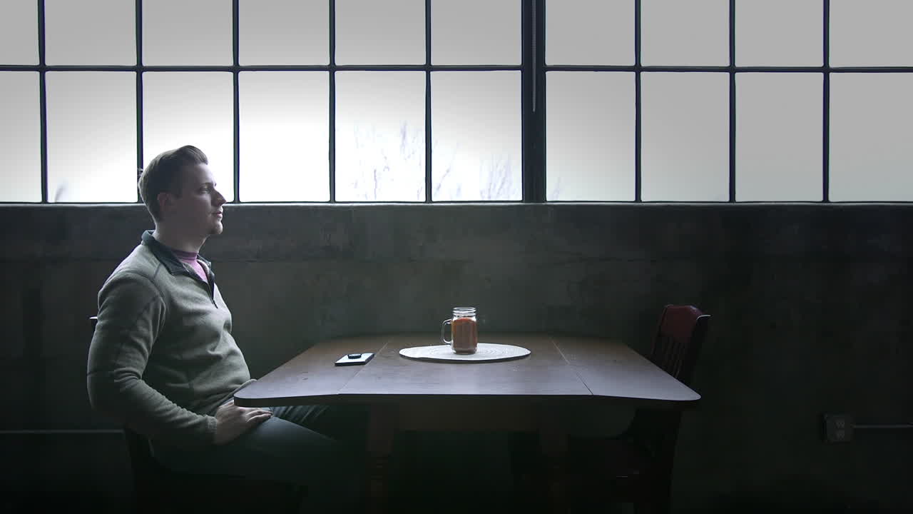 미래에 대해 생각하면서 슬픈 청년이 다락방에 있는 테이블에 앉아 있다