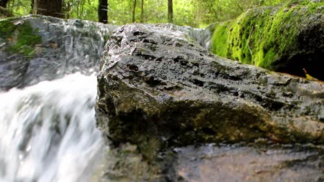 sped up waterfall, wide angle close up view of a large wet rock
