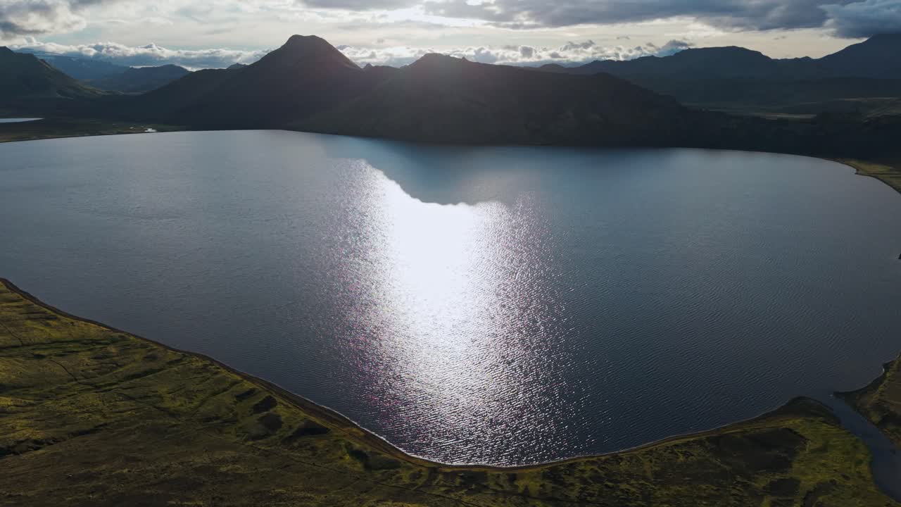 Vista aérea de águas reflexivas e encostas acidentadas, onde manchas verdes encontram a terra escura em uma beleza remota