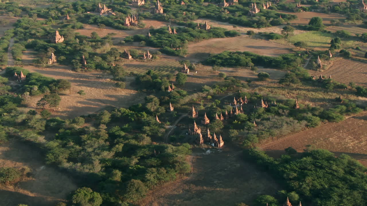toma aérea inclinada hacia arriba de la famosa pagoda dhammayazaka, con muchos templos más pequeños dispersos en llanuras rurales en myanmar