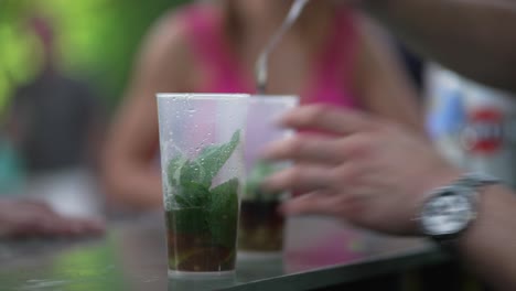 stirring a minty concoction in a transparent cup