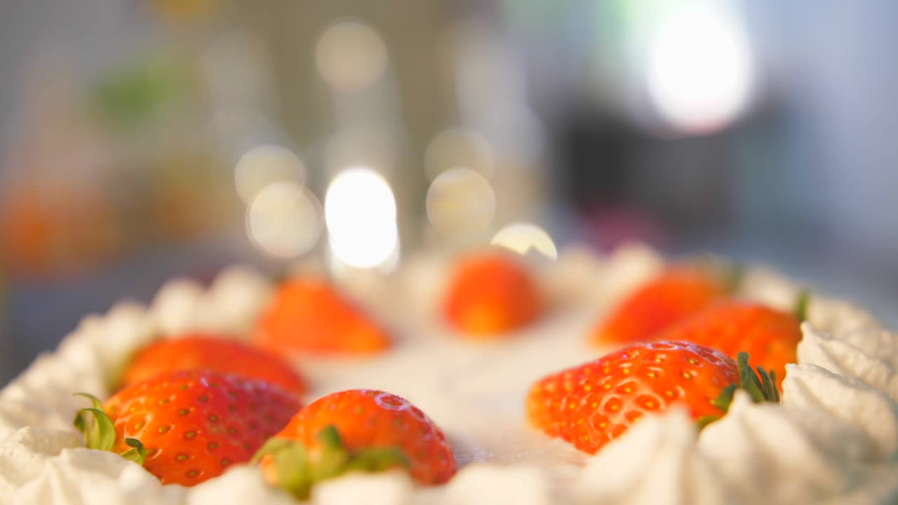 gira pastel de fresa en un hermoso fondo de iluminación. hermoso pastel con fresas y crema rotación en cámara lenta en el café, panadería que se prepara para la fiesta de cumpleaños feliz para el amor.