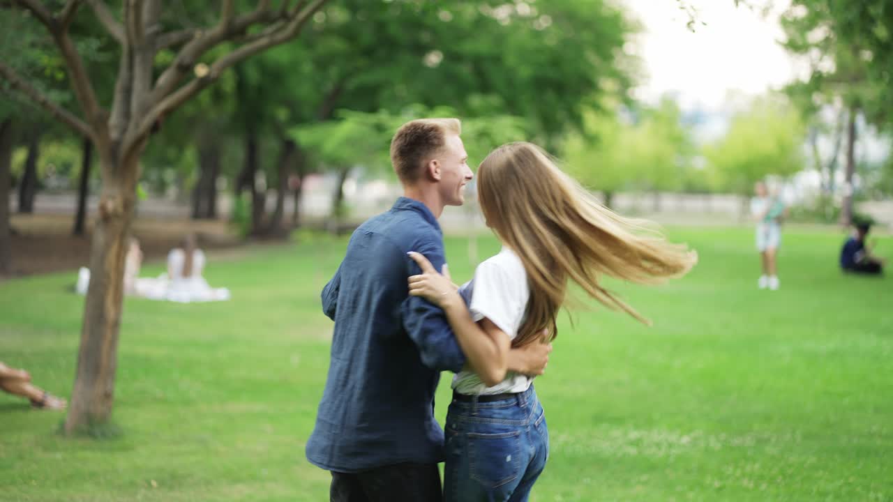 el chico baila con la chica en el parque. los jóvenes se toman de la mano y se divierten. felicidad