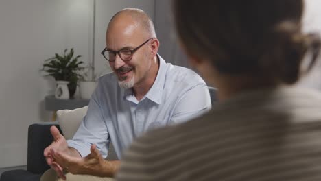 mature man sitting on sofa talking with female counsellor about general or mental health issue 15