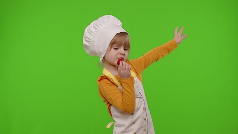 Child-girl-dressed-as-cook-chef-baker-in-apron-eats-delicious-fresh-strawberries-and-dances