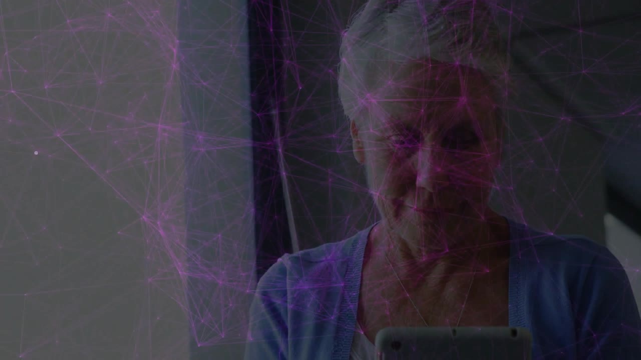 Senior woman lifting tablet by window activating purple graphic pulsing nodes monitoring network