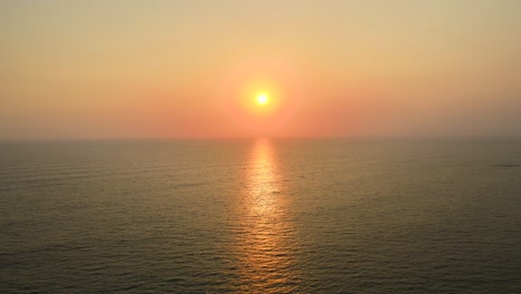 aerial drone shot of the sun setting over the ocean horizon