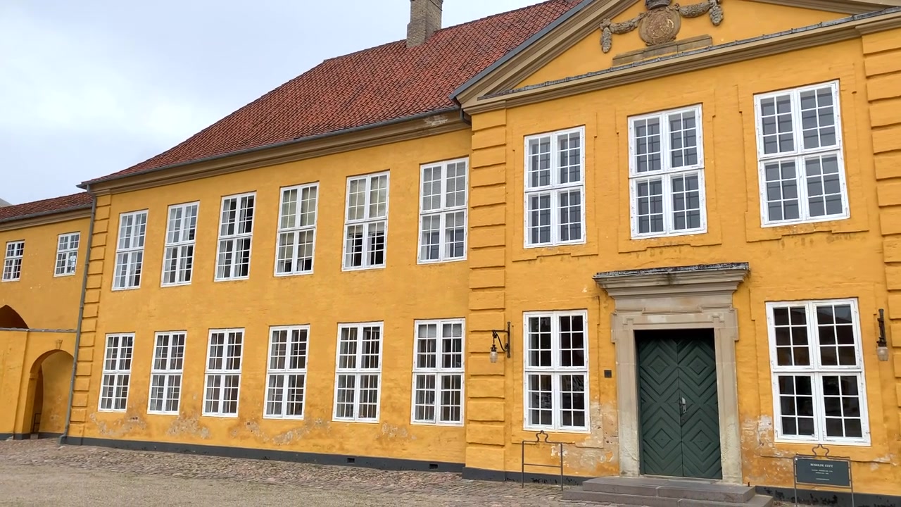 Roskilden kuninkaallinen palatsi Tanskassa, rakennettu vuosina 1733-1736. Roskilden tuomiokirkko on tämän eloisan keltaisen palatsin taustalla.