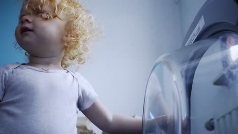 toddler opening the washing machine door and closing it in the laundry room