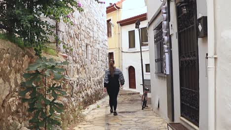 woman walking through an alley in a white town of santorini, greece