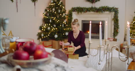 Mujer-Joven-Posicionamiento-Regalos-De-Navidad-Bajo-El-árbol