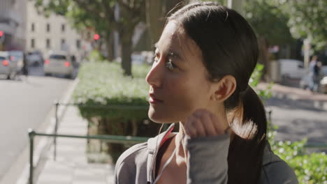 retrato de una joven asiática que se pone auriculares escuchando música disfrutando de un relajado día soleado en el fondo de la calle de la ciudad urbana