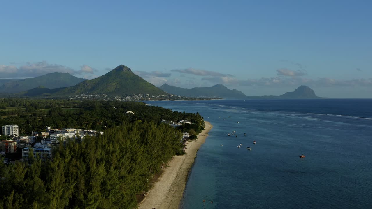 drone aéreo que se eleva sobre la costa de mauricio, horizonte de montaña en un cielo azul claro, islas paradisíacas