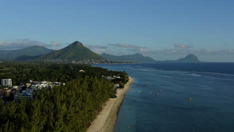 Drone-Aéreo-Que-Se-Eleva-Sobre-La-Costa-De-Mauricio,-Horizonte-De-Montaña-En-Un-Cielo-Azul-Claro,-Islas-Paradisíacas