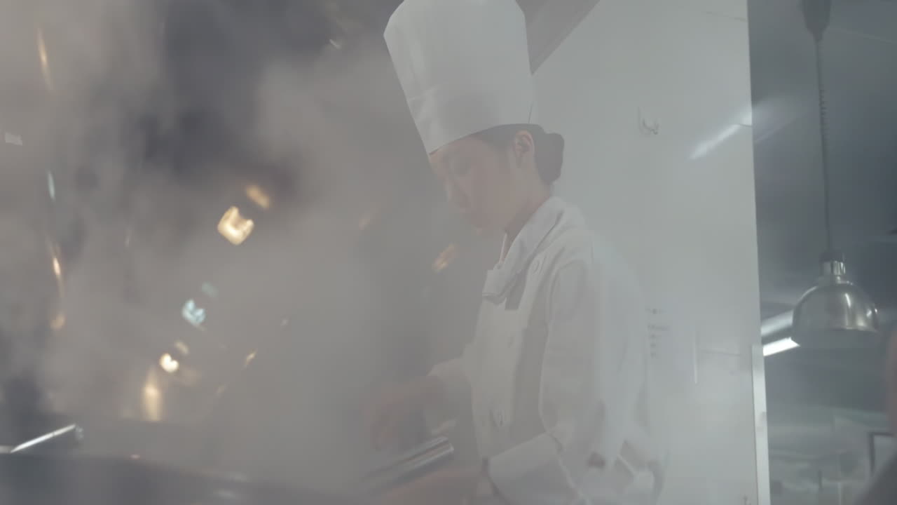 Professional Chef in uniform hold wok with fire at kitchen restaurant. Portrait of cook man with wok. Flambler or cooking vegetables with spices on natural fire