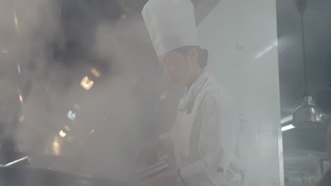 professional chef in uniform hold wok with fire at kitchen restaurant. portrait of cook man with wok. flambler or cooking vegetables with spices on natural fire
