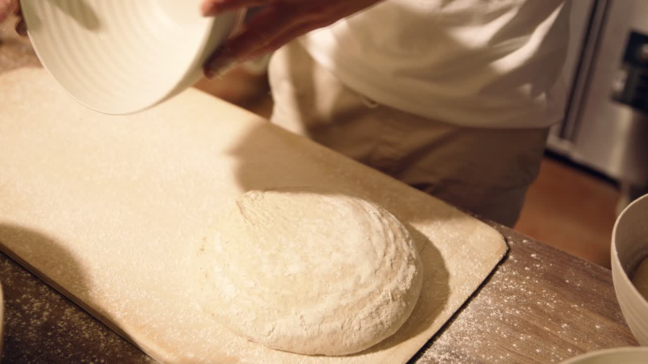 Baker's Hands Releasing Fresh Dough from a Bowl onto a Floured Board