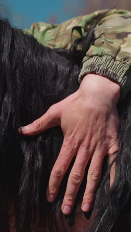 man hand pets chestnut horse with black mane neck communicating with animal at countryside closeup. farmer with equine creature at ranch slow motion