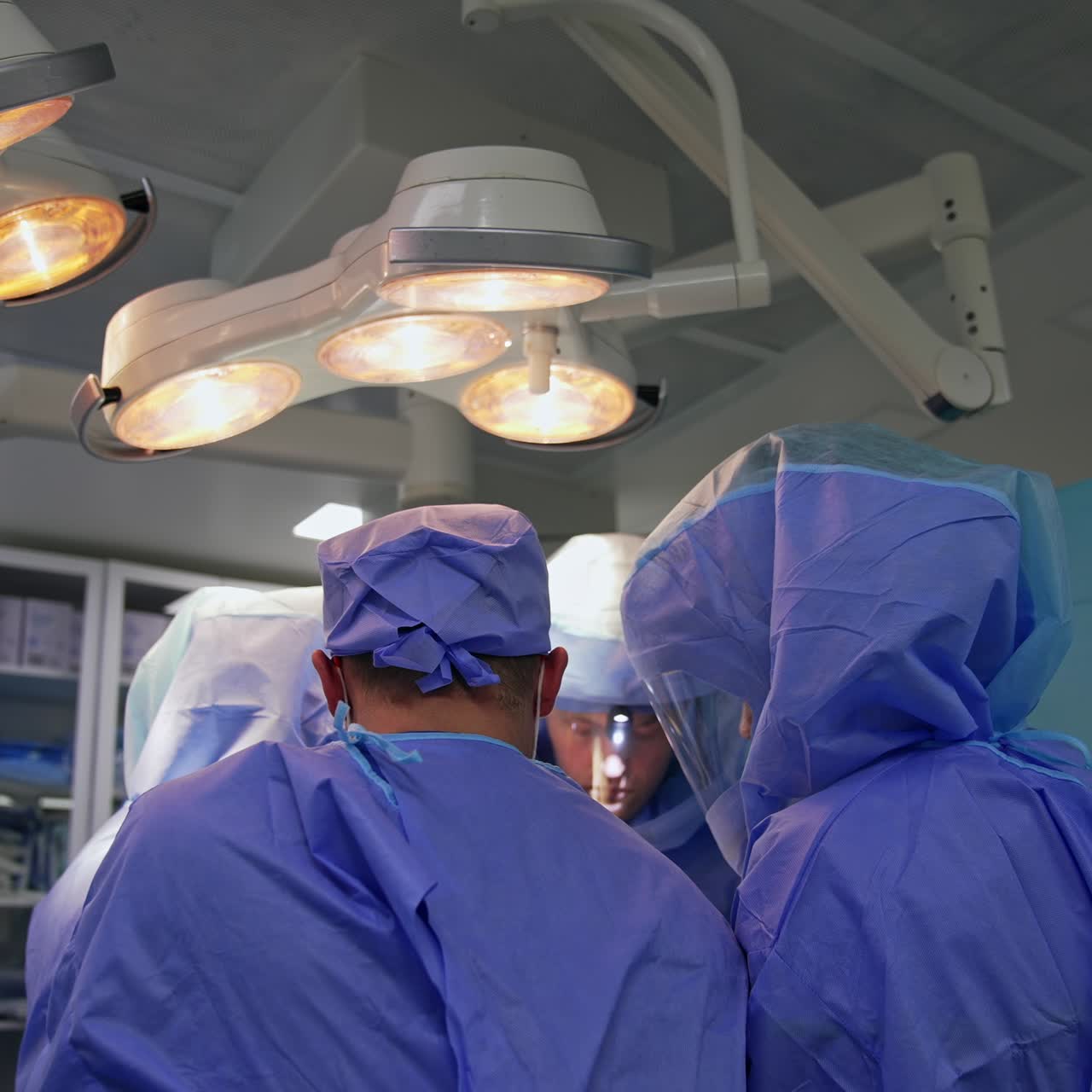 Group of medics standing close to each other collaborate at surgery. Three medics of a team work in protective suits