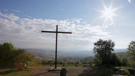 a large cross overlooking a scenic cityscape under a bright sunny sky