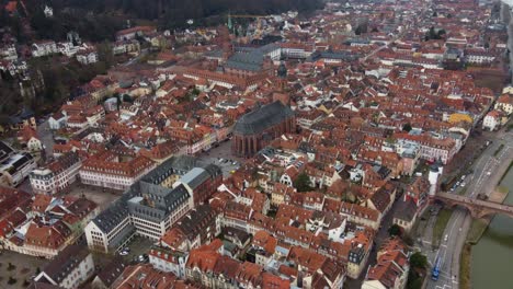 Medieval-Town-Church-amid-Red-Brick-Rooftops-of-Heidelberg-in-Germany,-Drone-View