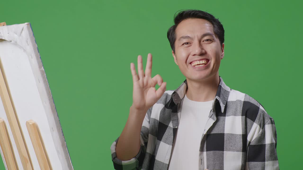 Smiling Artist Showing Ok Sign in Front of Easel
