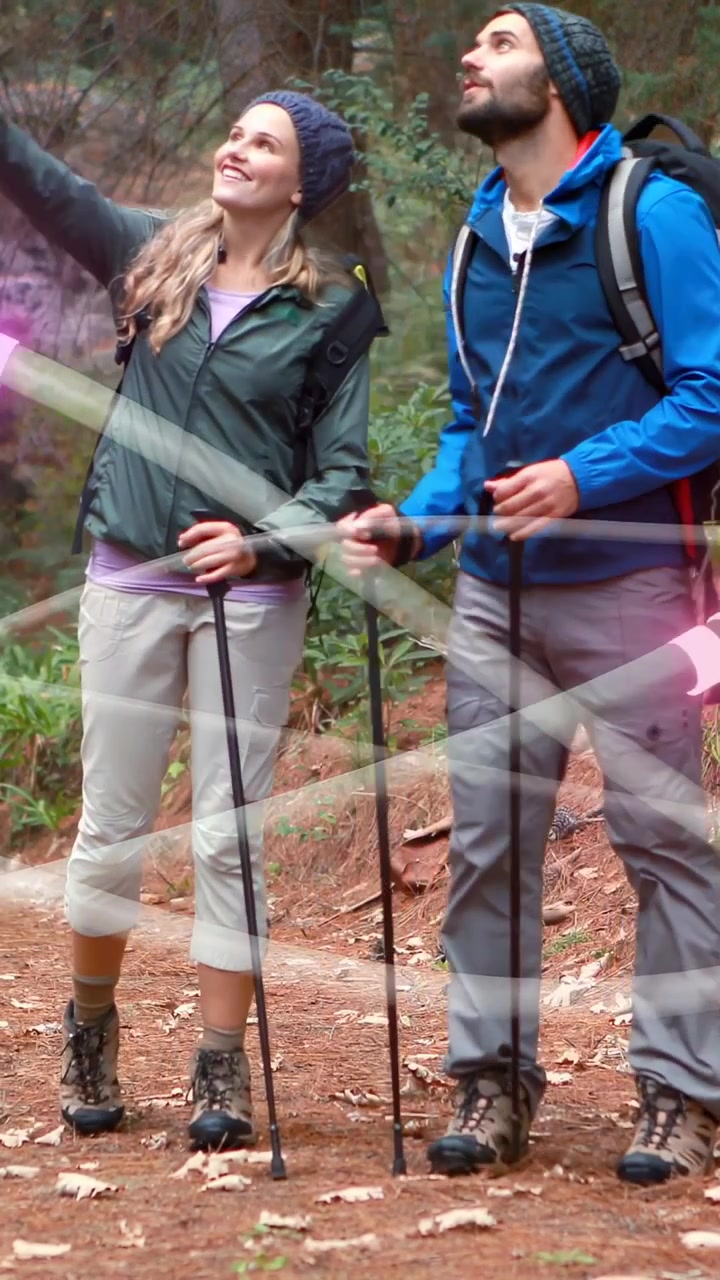 Video verticale: Donna che indica in alto, uomo che si gira mentre fa escursioni condividendo la vista, con striature dell'obiettivo sugli escursionisti.