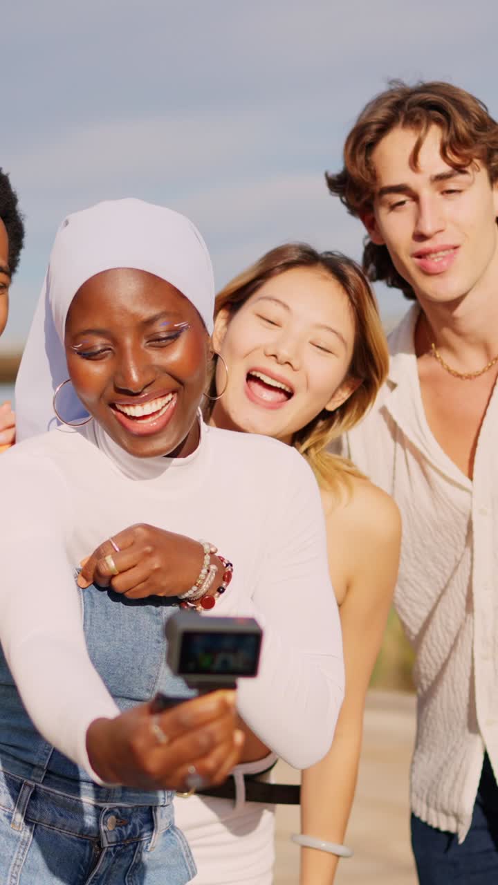 Multi-ethnic friends recording a video with small camera outdoors