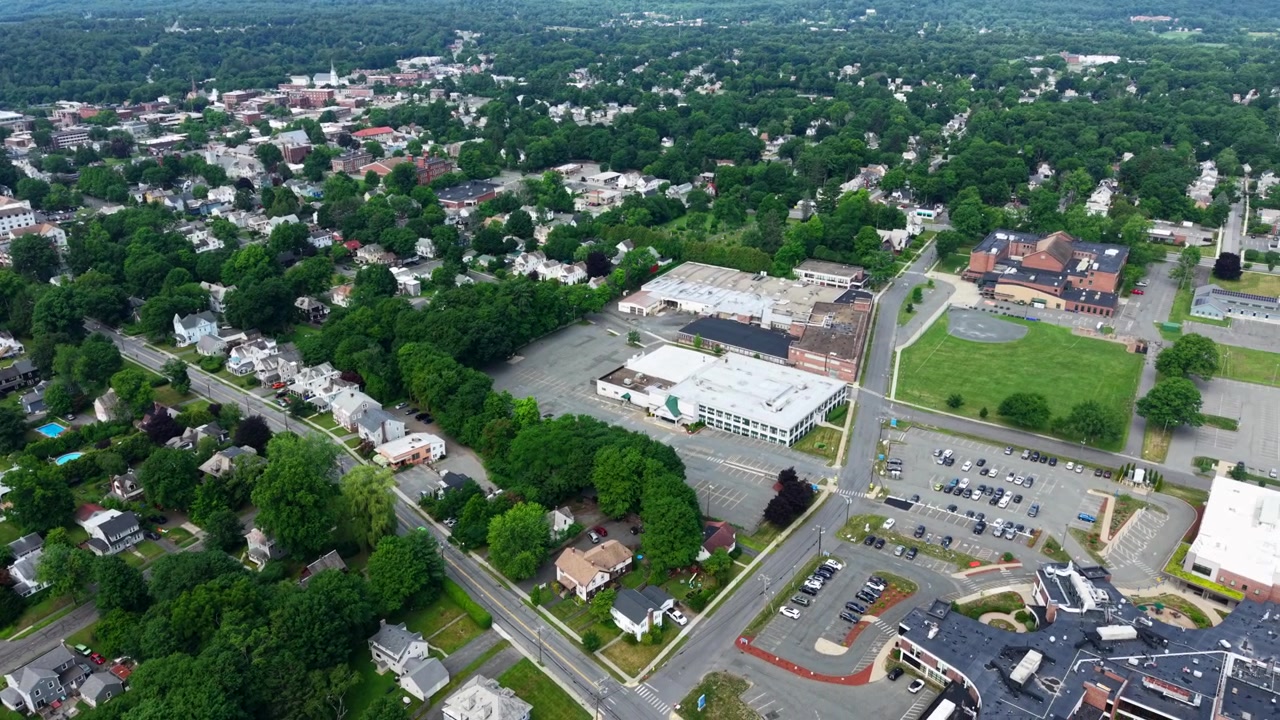 Panoramaudsigt med drone over Greenfields centrum og boligområde med industrianlæg i forstadsområdet ved tæt grøn skov, Massachusetts, USA.