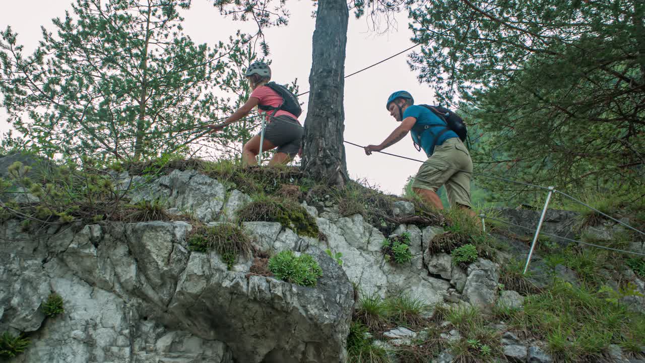 slow motion of a sportive couple climbing a steep rocky hill, Crna na Koroskem
