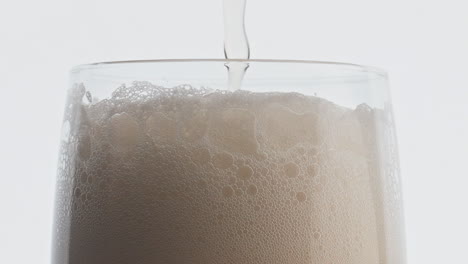 foamy beer stream pouring glass closeup. unfiltered drink filling glassware