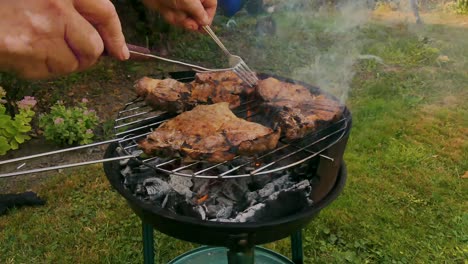 chief using fork and turning the meat on the grill