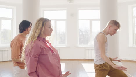 grupo multiétnico de bailarines contemporáneos entrenando movimientos de baile con los brazos en el aire en el estudio