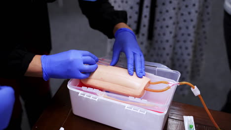 practical lesson with an injection. practitioner doing a training injection into a vein on a dummy. procedure of pricking into manikin arm. close-up.