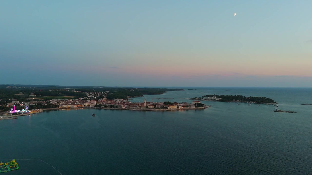 Parenzo Croazia al tramonto, vista aerea con drone della splendida città vecchia, hotel costieri, spiagge soleggiate, lungomare, ruota panoramica e giostre durante una calda serata estiva sulla costa adriatica