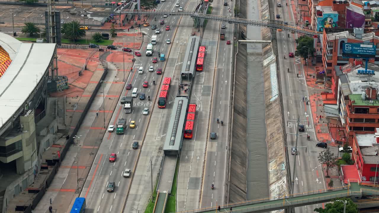 70mm aerial establishing cinematic orbit isolating two transmilenio stations in Bogota, Colombia with low traffic on NQS avenue.