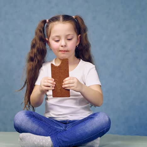 una chica comiendo una barra de chocolate.